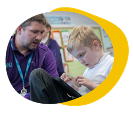 A teaching assistant sitting with a child using Grid for iPad.
