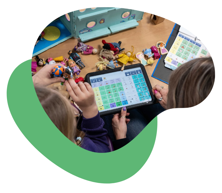 Child and adult using Grid for iPad during play with dolls and toys on a table.