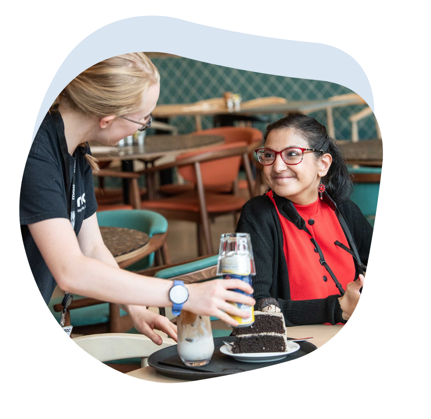 An image of a woman using her Talk Pad with a waitress at a cafe.