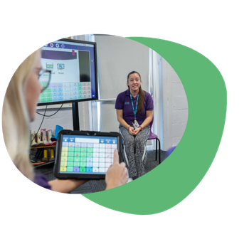 Grid for iPad in a classroom setting with a Teaching Assistant using it with a student.