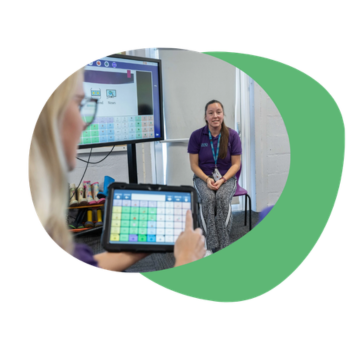 Specialist teacher at the front of the classroom with a large electronic whiteboard featuring Grid