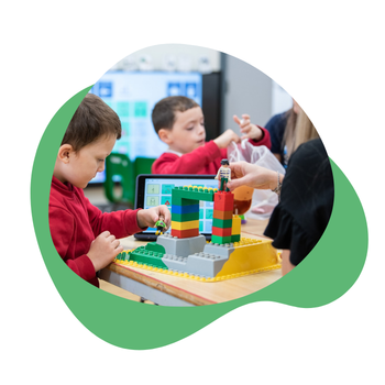 A child playing with Lego in the classroom with his teacher.