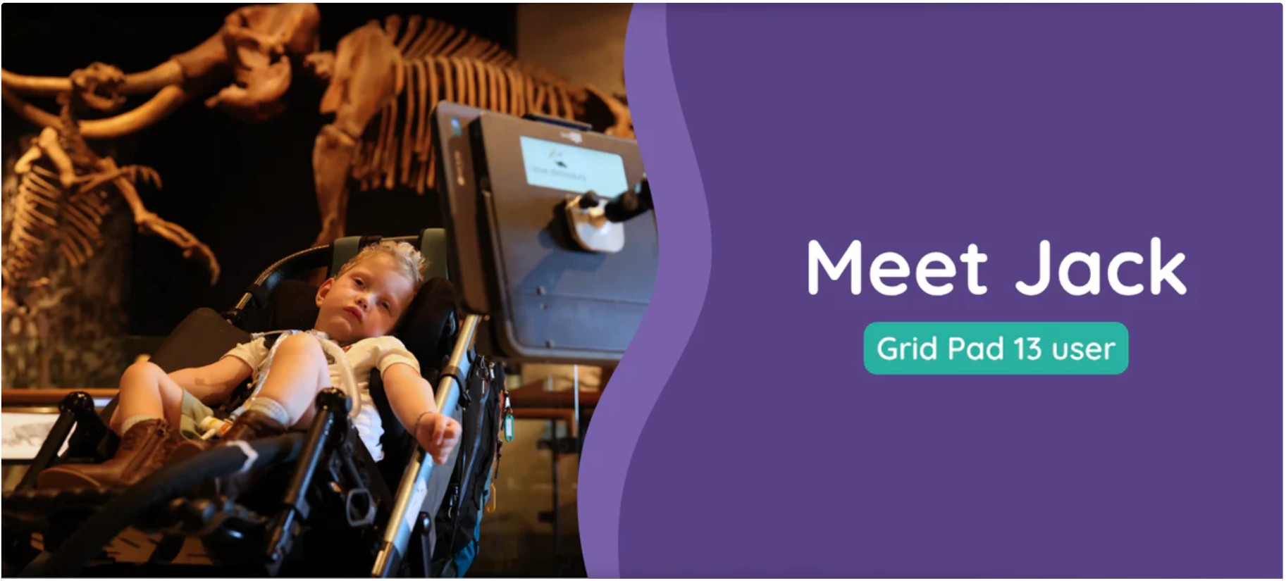 Meet Jack. Jack is in his chair with Grid Pad device at a museum with dinosaur skeletons behind him.