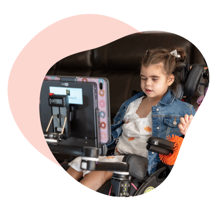 An AAC user sitting in her wheelchair with her Grid Pad AAC device mounted in front of her.