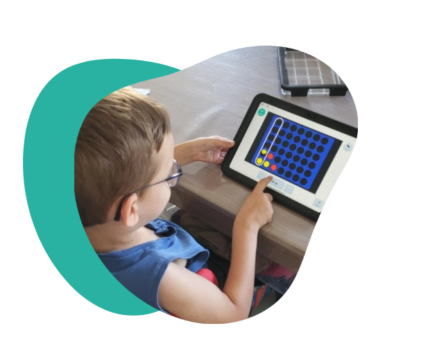 Photo of Nael using his Talk Pad, tapping the screen with one finger while seated at a table.